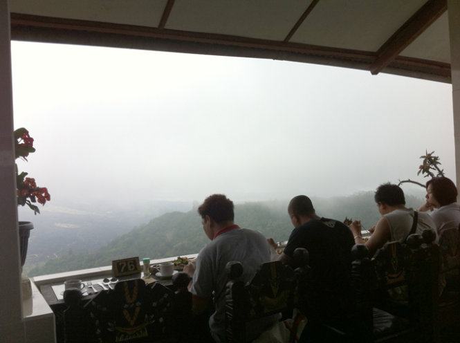 Du khách nước ngoài đang thưởng thức ẩm thực Bali, trước mặt là ngọn núi lửa Batur danh tiếng trong một ngày đầy sương mù&nbsp;- Ảnh: Thủy OCG